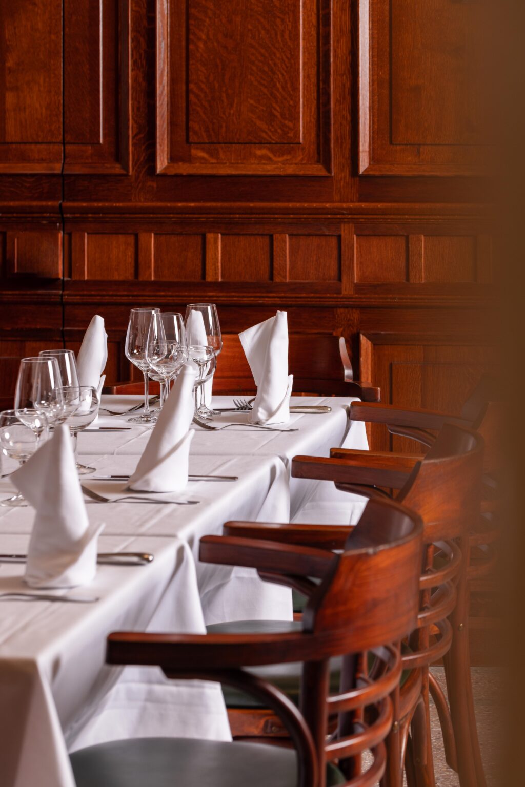 Salle aux boiseries de l’Auberge du Mouton Blanc, tables dressées et chaises bistrot
